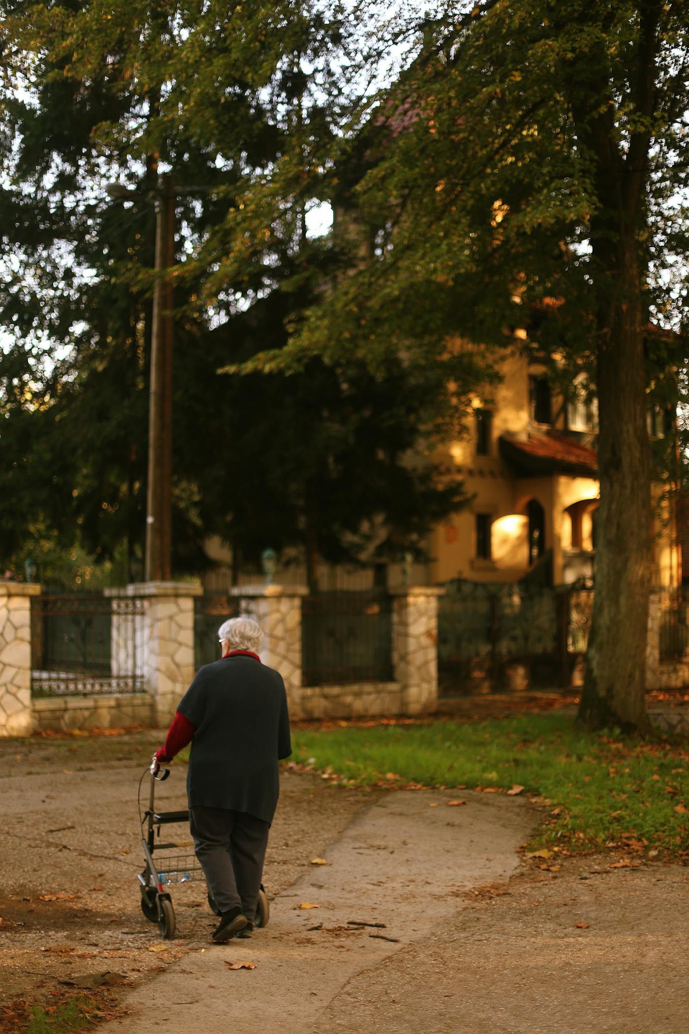 Pessoa idosa caminhando em área arborizada com auxílio para mobilidade.
